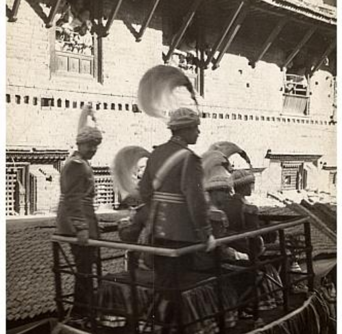 Men in uniform with large plumed hats on elephant